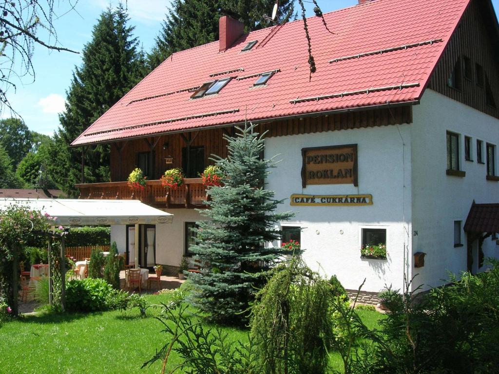 een groot wit gebouw met een rood dak bij Pension Roklan in Železná Ruda