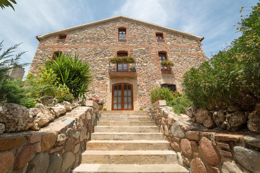 - un bâtiment en pierre avec des escaliers menant à une porte dans l'établissement Rincón de piedra BCN, à Corró de Vall