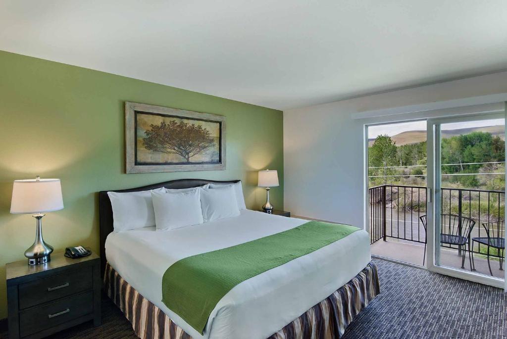 a bedroom with a large bed and a balcony at Oxford Suites Yakima in Yakima