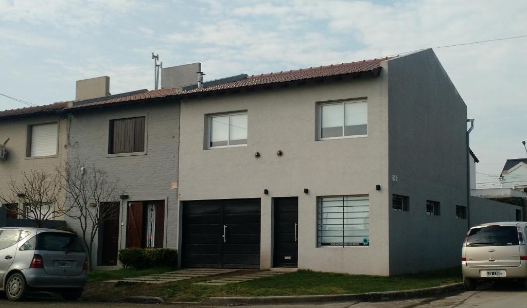 una casa con dos coches estacionados frente a ella en Apartamento La Felicidad, en Tandil
