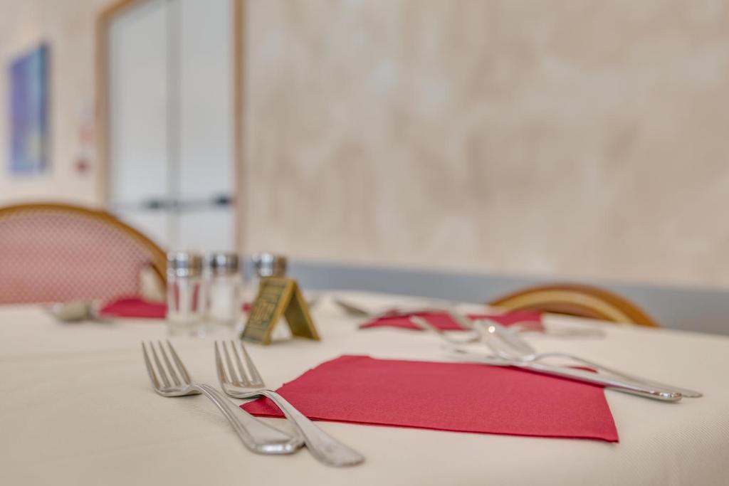 a table with a red napkin and silverware on it at Hotel Ambassador in Caorle