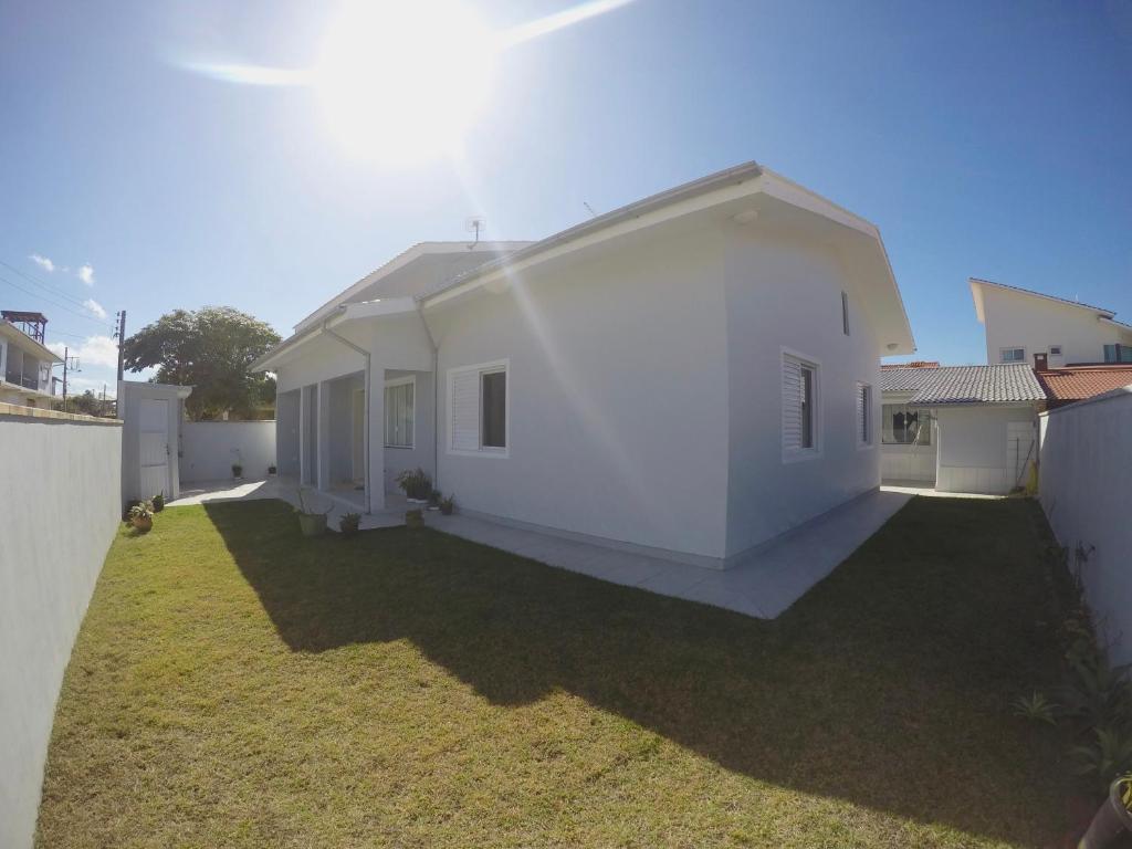 a large white house with a grass yard at Casa na Praia da Vila in Imbituba