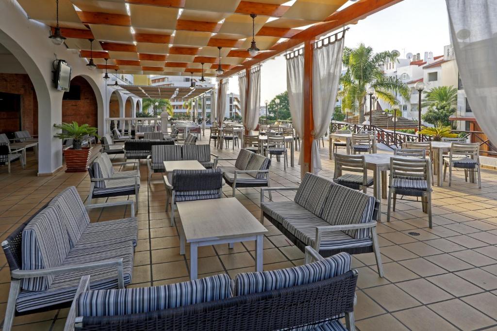 un patio al aire libre con sillas, mesas y sillas en Aparthotel Paladim & Alagoamar, en Albufeira