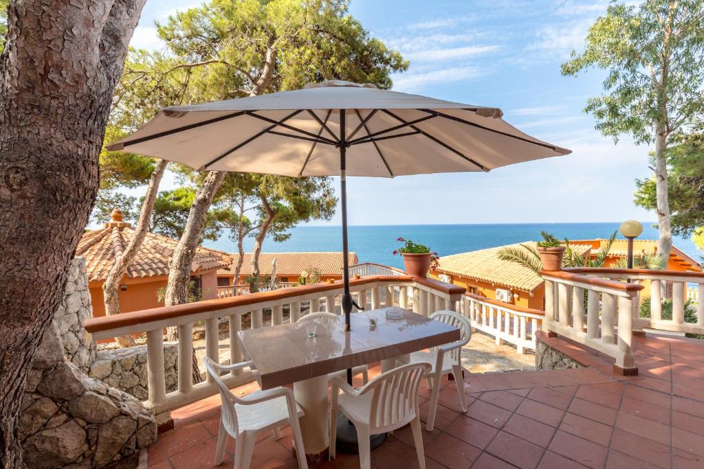バゲリーアにあるSolemar Sicilia - Residence Mer et Soleilのテーブルと椅子、パラソル付きのデッキ