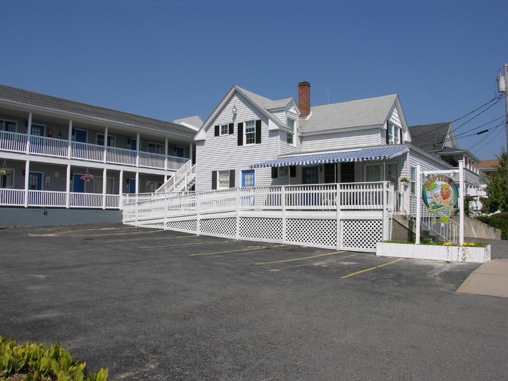 a white building with a parking lot in front of it at Neptune Motel Maine in Old Orchard Beach
