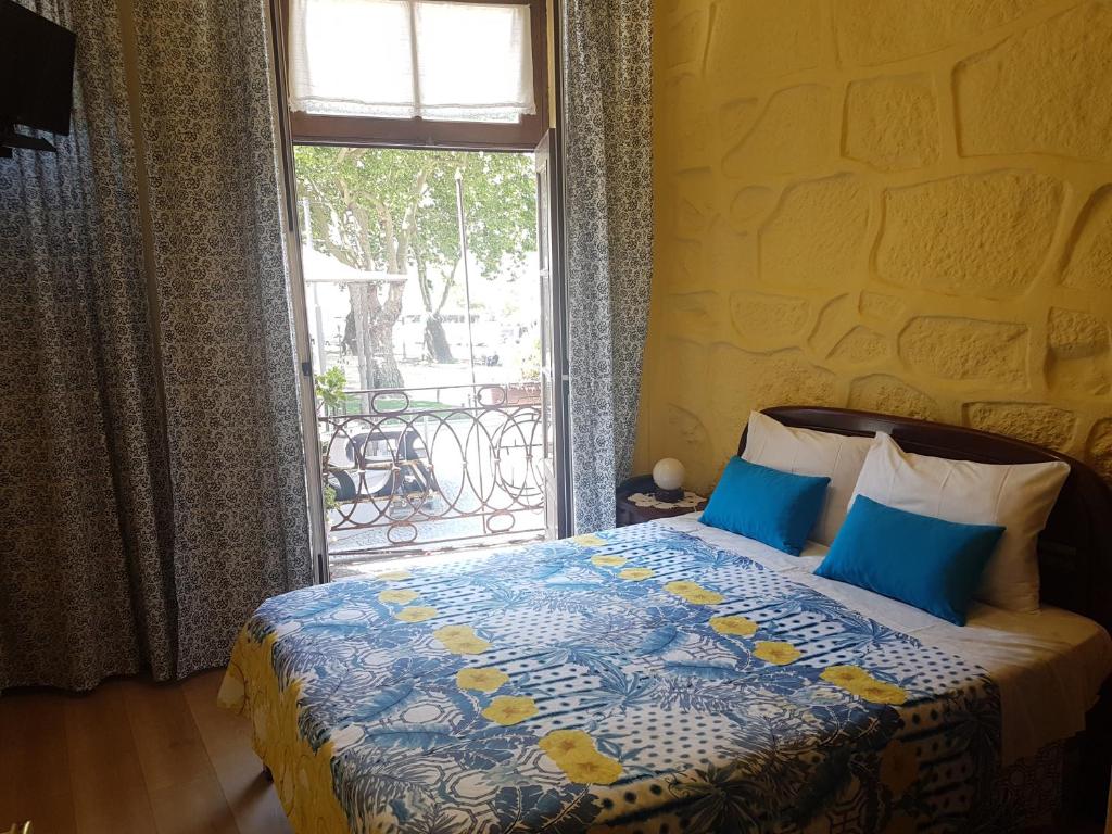 a bedroom with a bed with blue pillows and a window at Caldeira Guest House in Porto