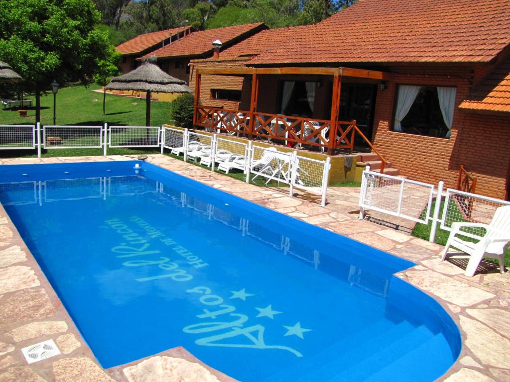 a large blue swimming pool in front of a house at Hotel Altos del Rincon in Merlo