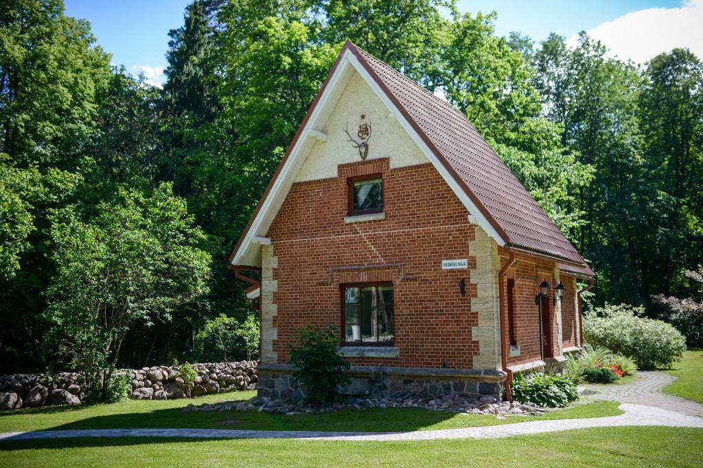 uma pequena casa de tijolos com um telhado de gambrel em Mednieku Namiņš em Sigulda