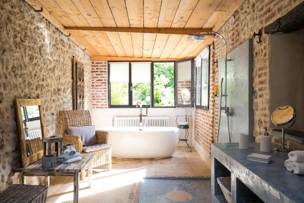 a bathroom with a tub in a room with brick walls at La Maison Du Parc in Honfleur