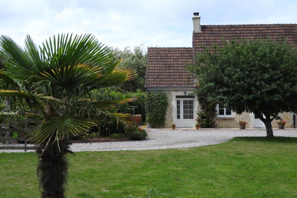 a house with a palm tree in front of a yard at Chambres d'Hotes Elvire et Laurent Barbey in Sainte-Marie-du-Mont