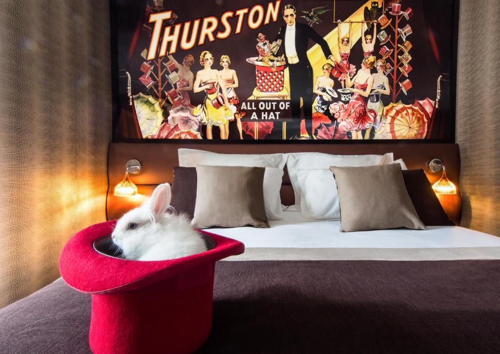 a white rabbit sitting in a red chair next to a bed at Hotel Splendor Elysées in Paris
