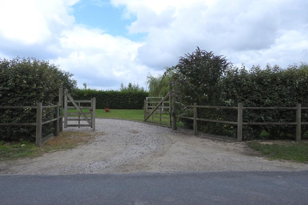 a fence with a gate on a dirt road at Chambres d'Hotes Elvire et Laurent Barbey in Sainte-Marie-du-Mont