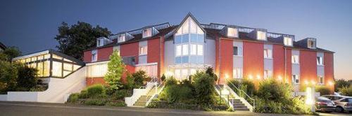 un gran edificio rojo con coches estacionados en un estacionamiento en Main Hotel Eckert 3-Sterne Superior, en Margetshöchheim