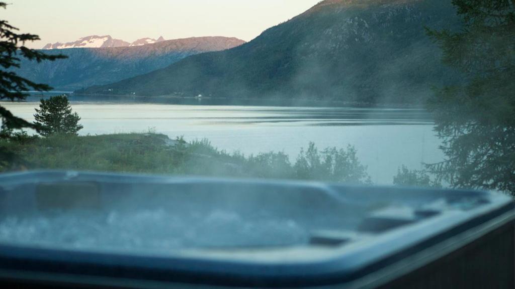 a bath tub with a view of a lake and mountains at Stetind Hotel in Kjøpsvik
