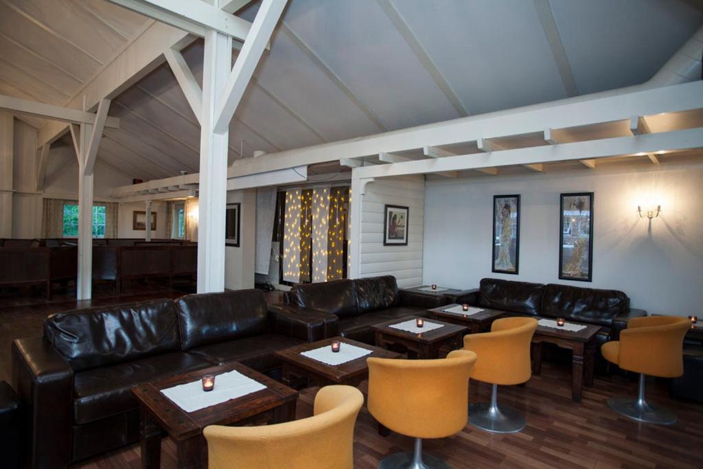 a living room with a leather couch and tables and chairs at Stetind Hotel in Kjøpsvik