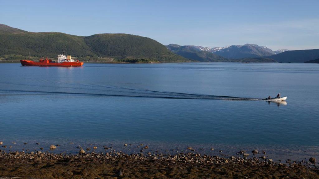 a boat in a body of water with a red ship at Stetind Hotel in Kjøpsvik