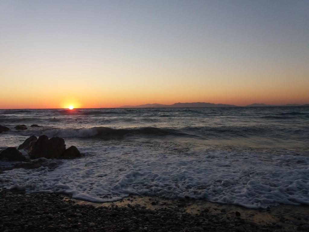a sunset on a beach with the ocean at Annabel Apartments in Theologos