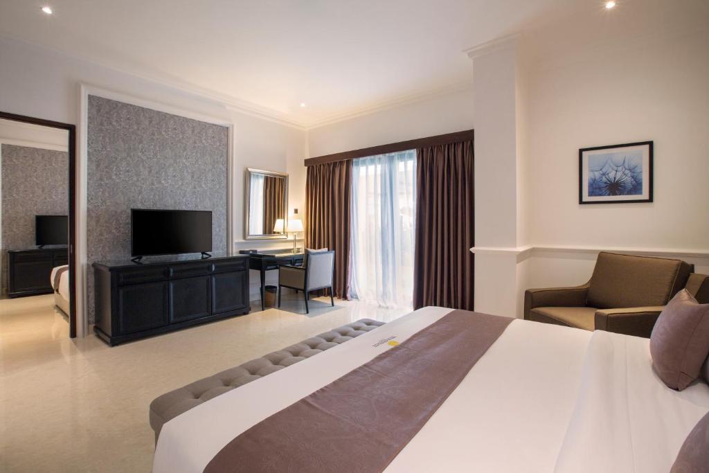 a hotel room with a large bed and a television at Grand Palace Hotel Sanur - Bali in Sanur