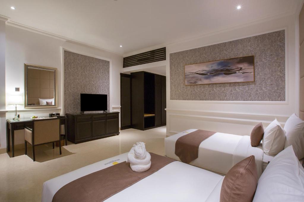 a hotel room with two beds and a desk at Grand Palace Hotel Sanur - Bali in Sanur