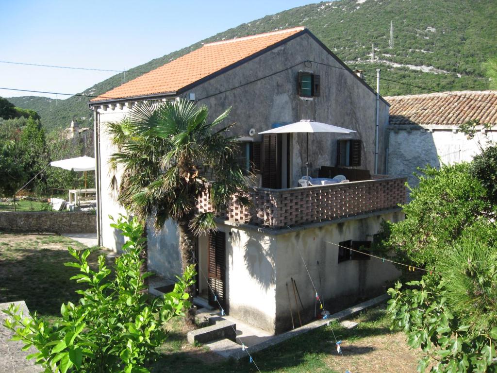 ein Haus mit Balkon und Sonnenschirm in der Unterkunft Apartment Sveti Jakov 37 in Sveti Jakov