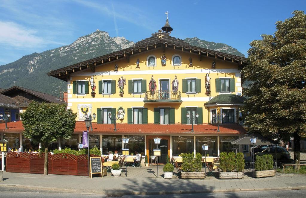 ein großes gelbes Gebäude vor einem Gebäude in der Unterkunft Atlas Posthotel in Garmisch-Partenkirchen