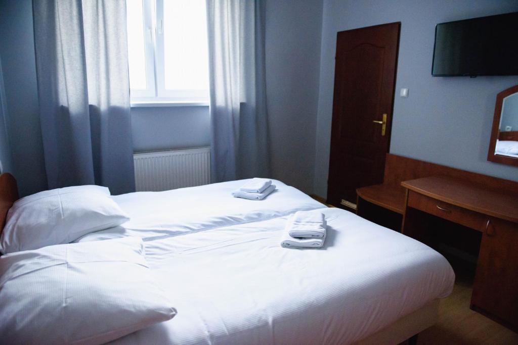 a hotel room with a bed with two towels on it at Hotel Turkovia in Turek