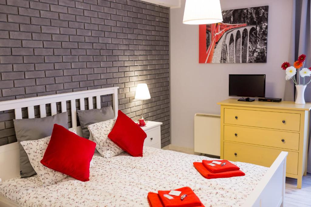 Un dormitorio con una cama con almohadas rojas. en Grey Studio II, en Wroclaw