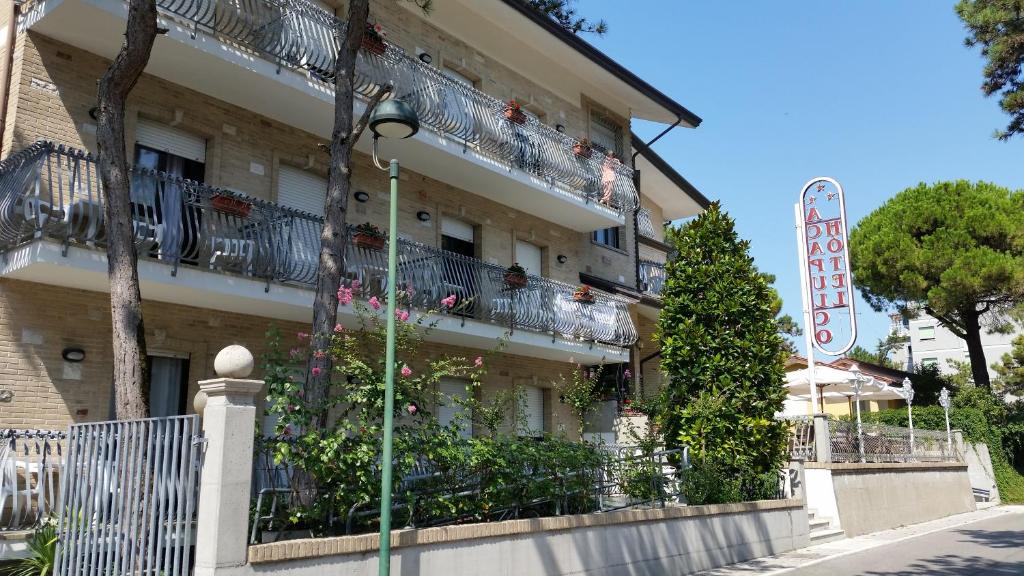 un edificio con flores y un cartel delante en Hotel Acapulco en Lignano Sabbiadoro