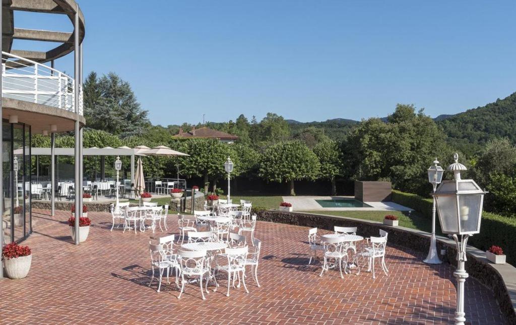 un patio con mesas y sillas blancas y una piscina en Hotel Riu Fluviá, en Olot