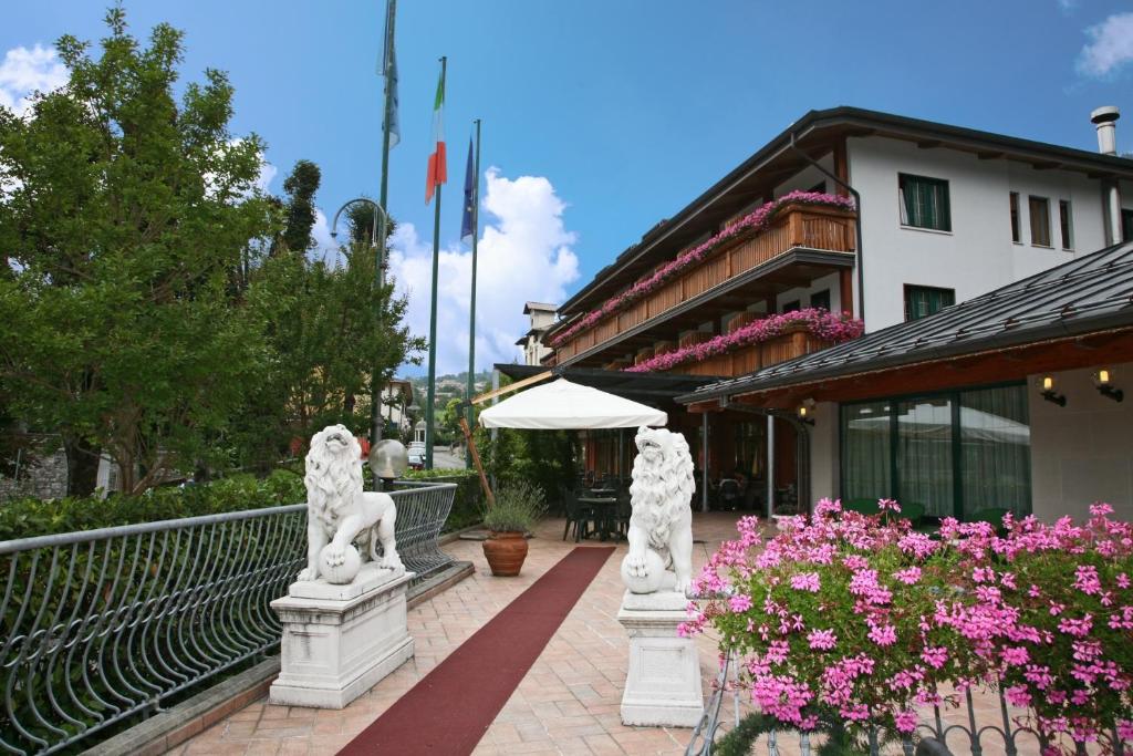 un complejo con estatuas frente a un edificio en Hotel Centro Benessere Gardel en Arta Terme