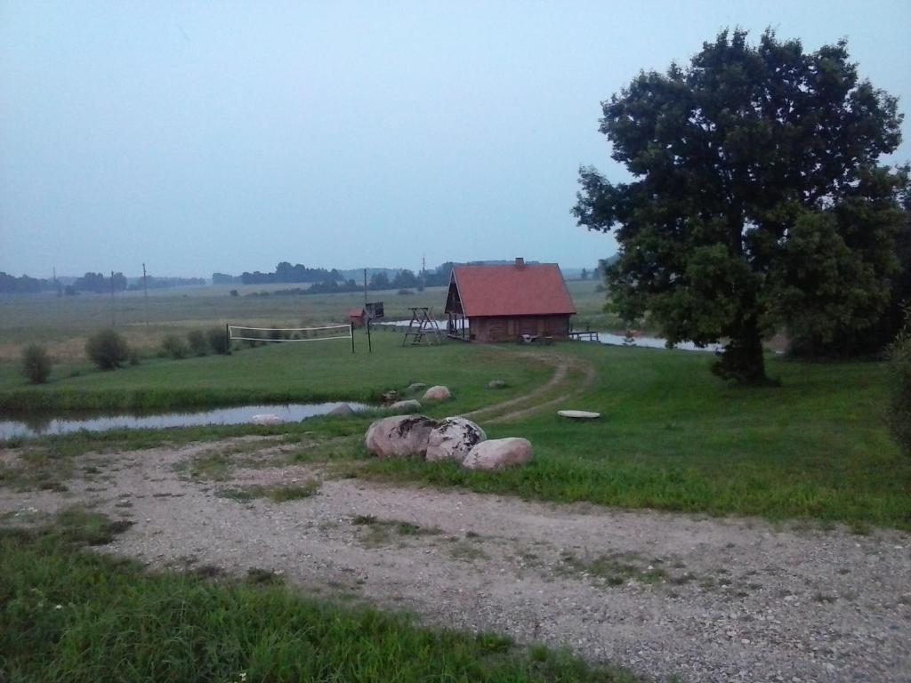 a barn in the middle of a field with some rocks at Krustceles in Baltinava