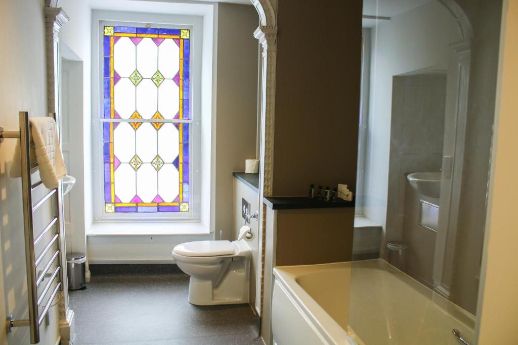 ein Bad mit einem WC und einem Buntglasfenster in der Unterkunft Plas Nanteos Mansion in Aberystwyth
