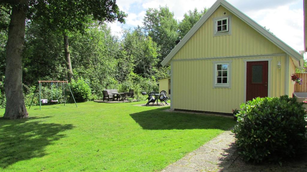une maison jaune avec une aire de jeux dans une cour dans l'établissement DeLay's Guest House, à Ängelholm
