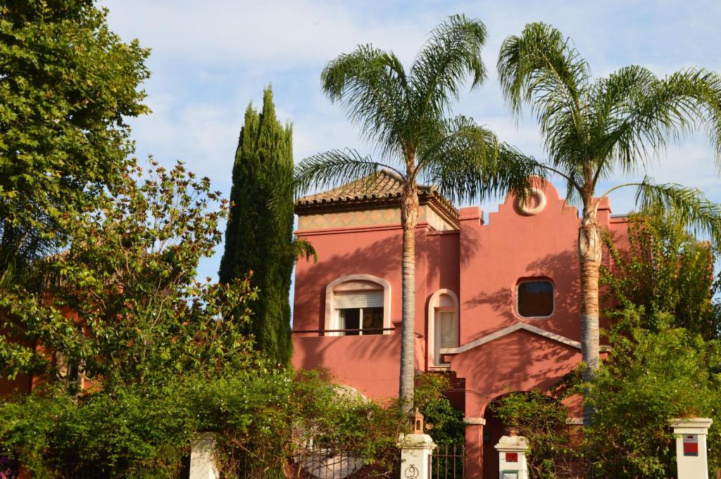 a red house with palm trees in front of it at Villa 9 La Alzambra-Puerto Banus in Marbella