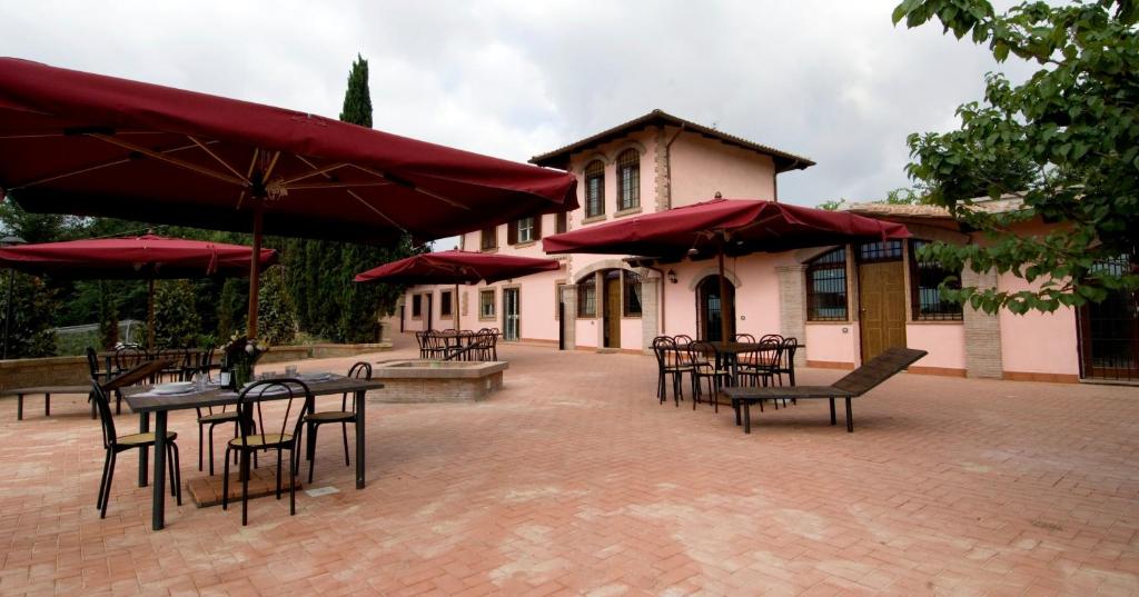 a patio with tables and chairs with red umbrellas at Azienda Agricola Sinisi in Cerveteri