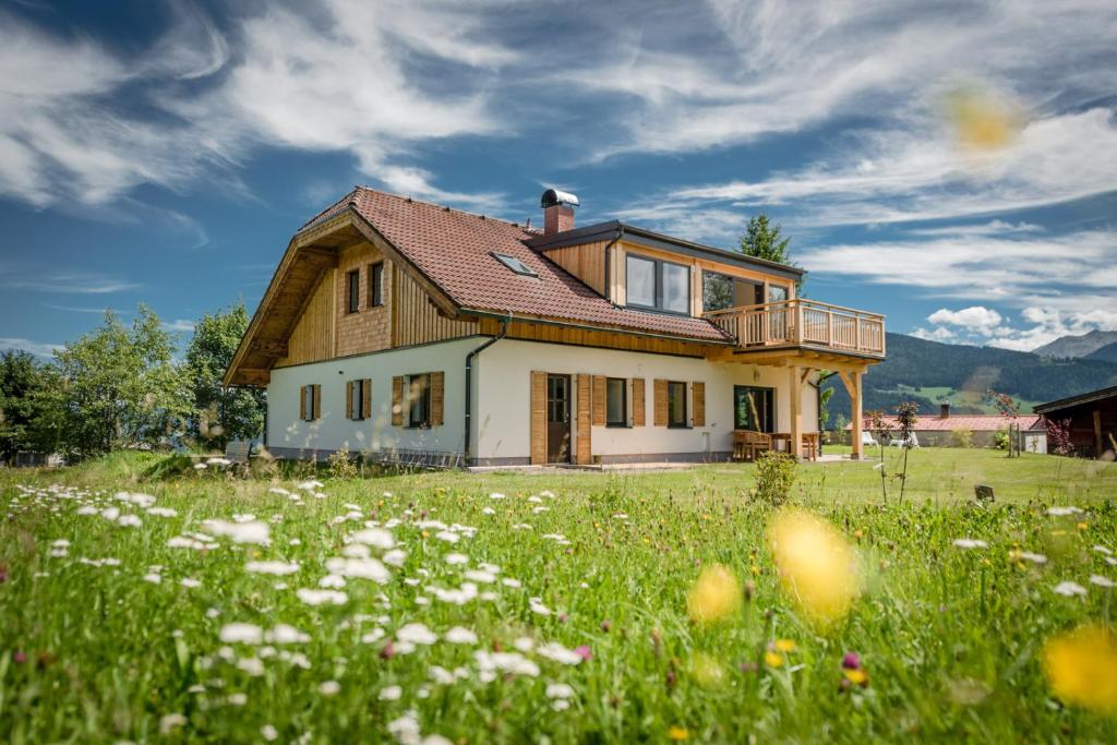 a house on a hill with a field of flowers at Naturchalet Höflehner - charming Hideaway & Summercard in Ramsau am Dachstein