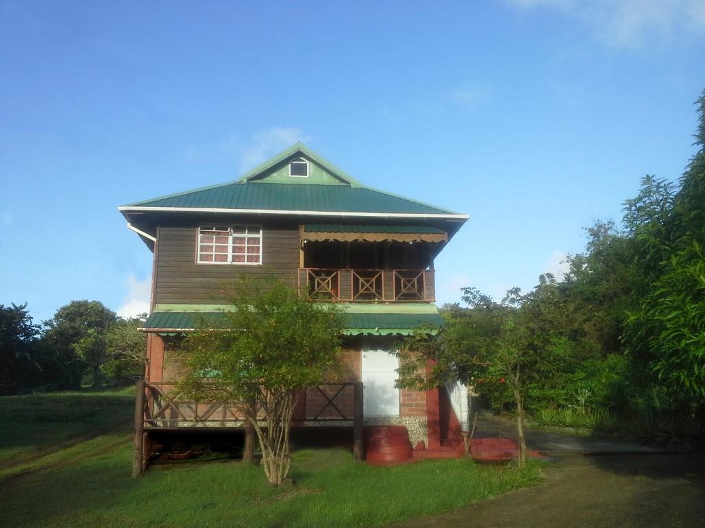 une maison avec un toit vert au-dessus dans l'établissement Seawind Cottage Authentic St.Lucian Accommodation near Plantation Beach, à Gros Islet