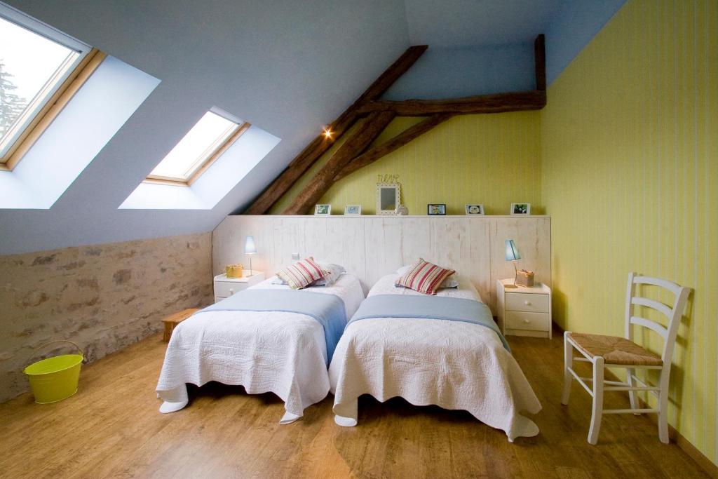 two beds in a room with two windows at Gite Le Meix Chapeau in Levernois