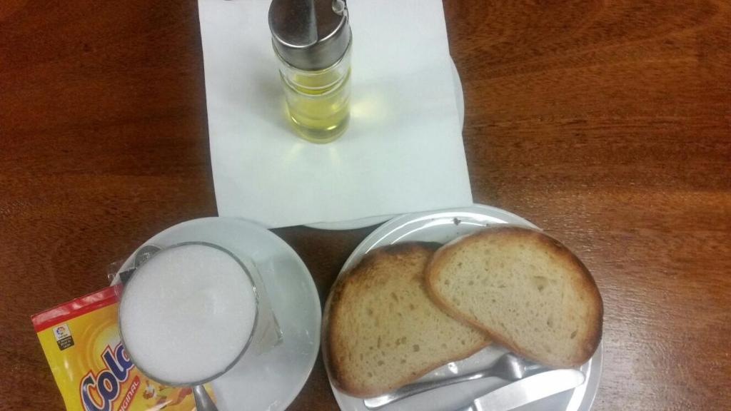 un morceau de pain et une tasse de café sur une table dans l'établissement Hostal Virgen de la Encina, à Ponferrada