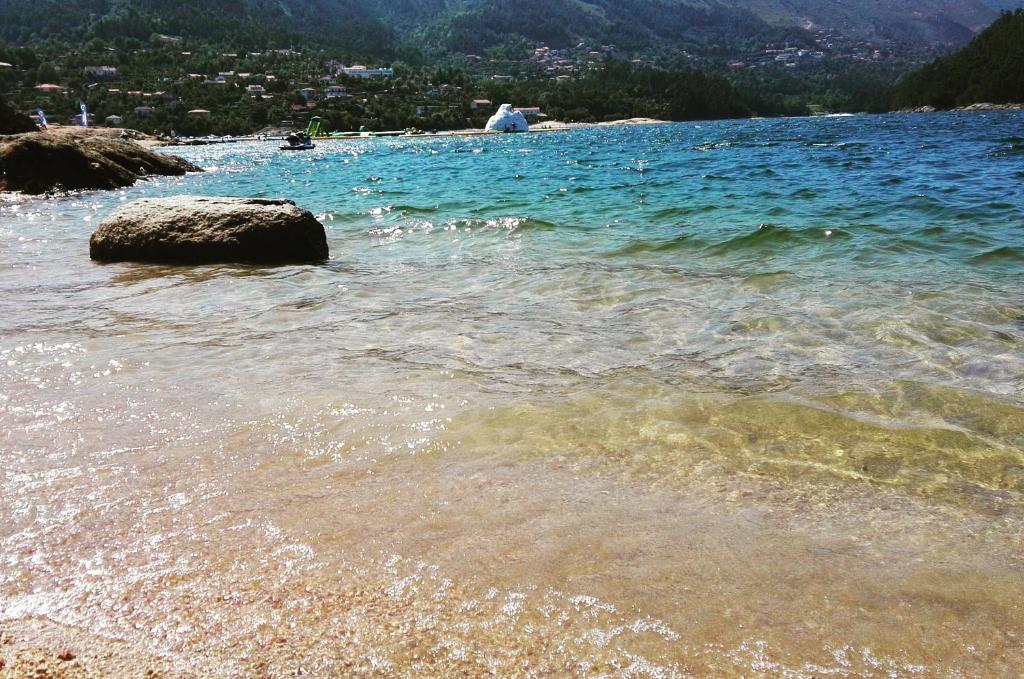 una playa con una gran roca en el agua en Alojamento Por do Sol, en Gerês