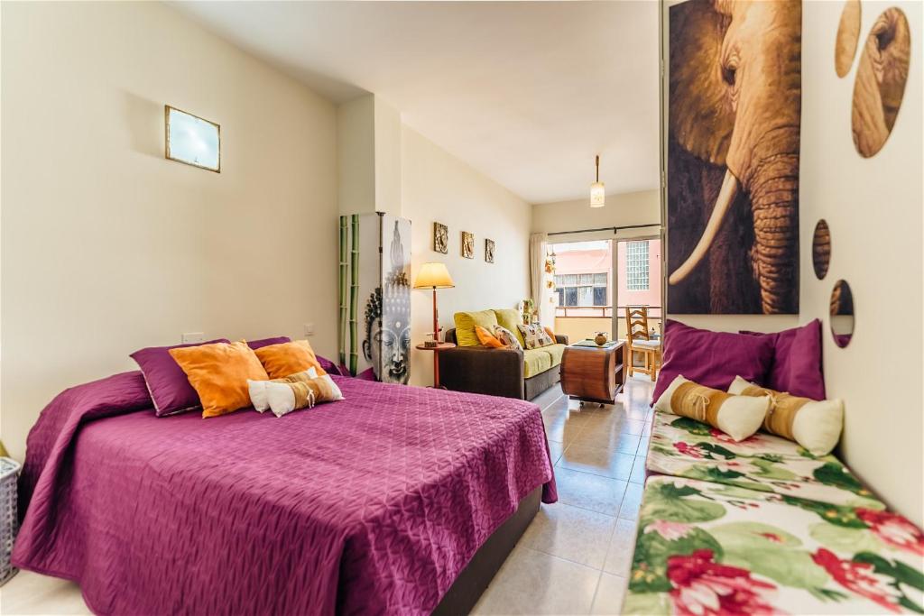 een slaapkamer met een paars bed en een woonkamer bij Al Golpito in Las Palmas de Gran Canaria