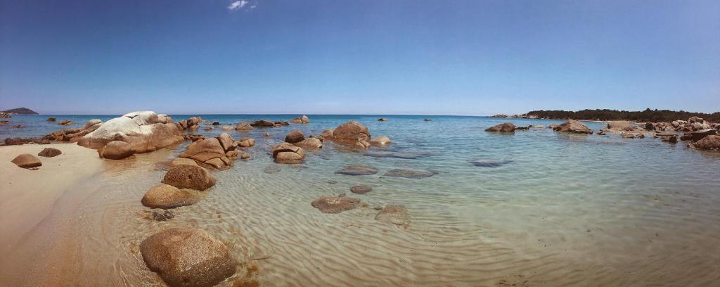 una playa con algunas rocas en el agua en Residence Verde Mare Official Site, en Tortolì