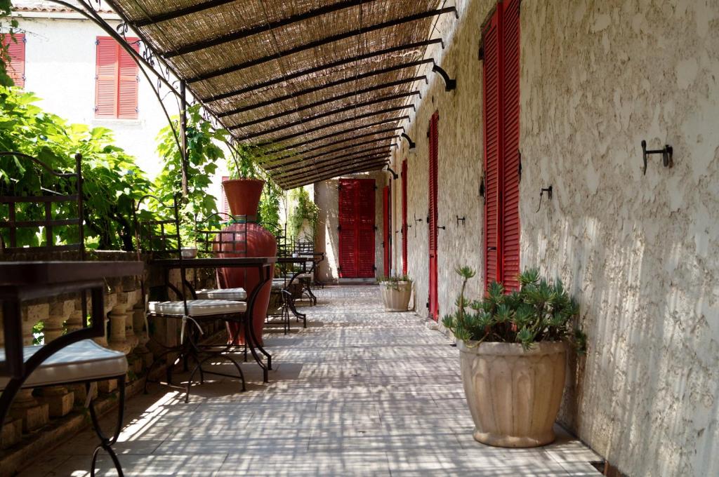 un patio extérieur avec des chaises, des tables et un auvent dans l'établissement Hôtel Les Orangers, à Hyères