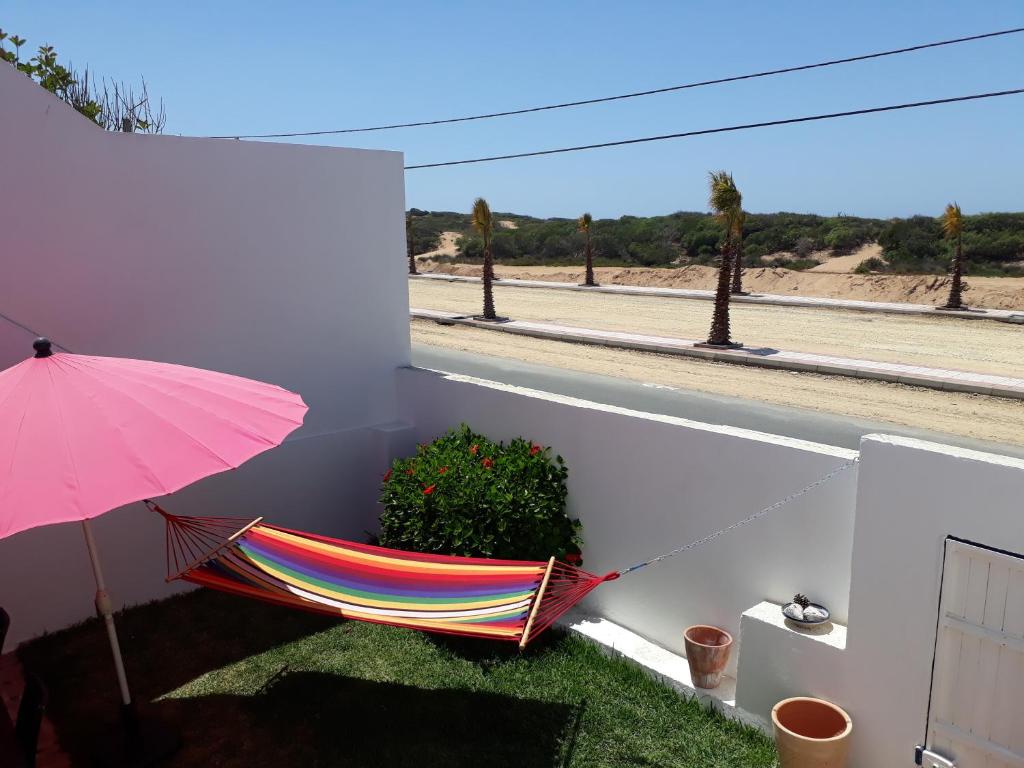 una hamaca sentada en un balcón con una sombrilla rosa en Villa Nour, en Oualidia
