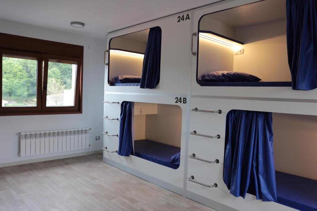 um quarto com 3 beliches com cortinas azuis em Zendoira em Palas de Rei 