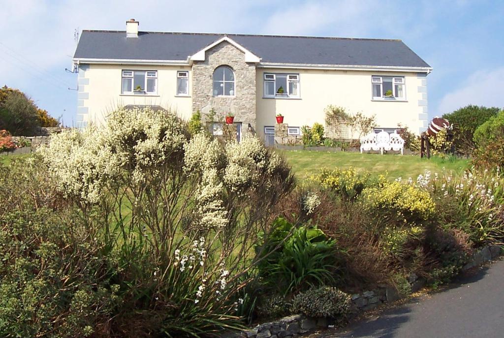 una casa blanca con flores delante de un patio en Buttermilk Lodge Guest Accommodation, en Clifden