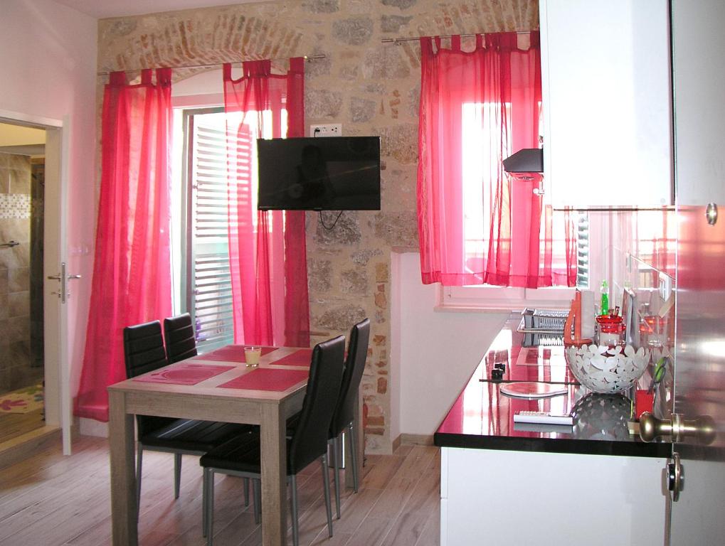 een keuken met roze gordijnen en een tafel met stoelen bij Apartmani KLARA i GRACIA in Split