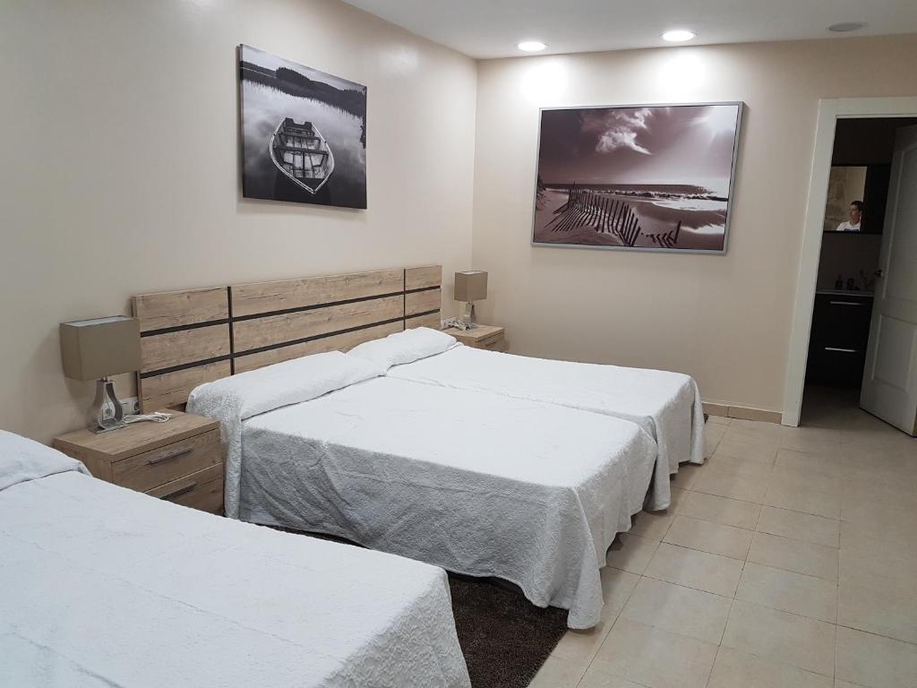 a bedroom with two beds and two pictures on the wall at Hogar del Puerto in Combarro