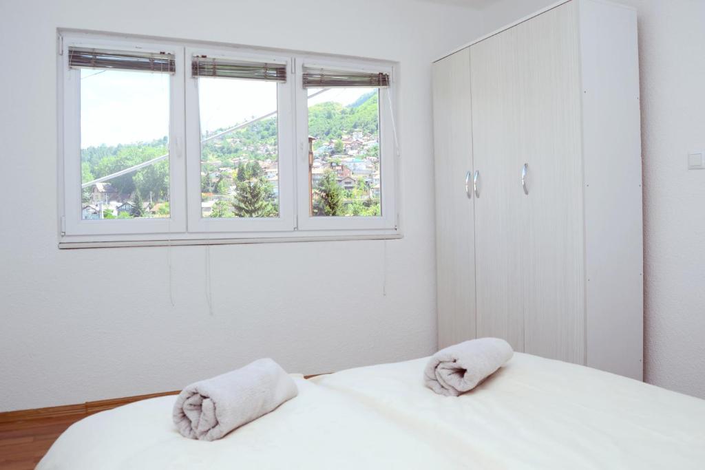 een witte slaapkamer met 2 handdoeken op een bed met een raam bij Apartmani Balibeg in Sarajevo