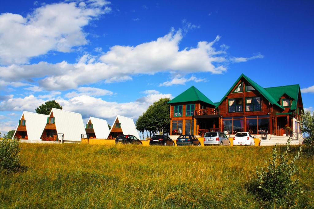 a large house with cars parked in a field at Etno selo Sljeme in Žabljak